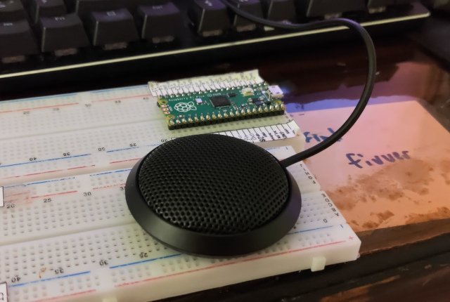 conference microphone sitting on a desk next to a pic pico